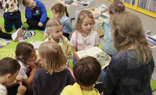bibliotekarka czyta zgromadzonym wokół niej dziećmi