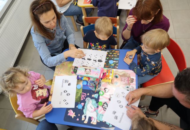 dzieci z rodzicami odbijają stempelki ze zwierzątkami