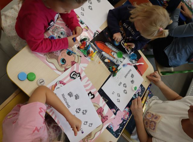 dzieci z rodzicami odbijają stemelki ze zwierzętami na kartkach