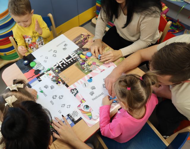 dzieci z rodzicami odbijają na kartkach stempelki ze zwierzętami