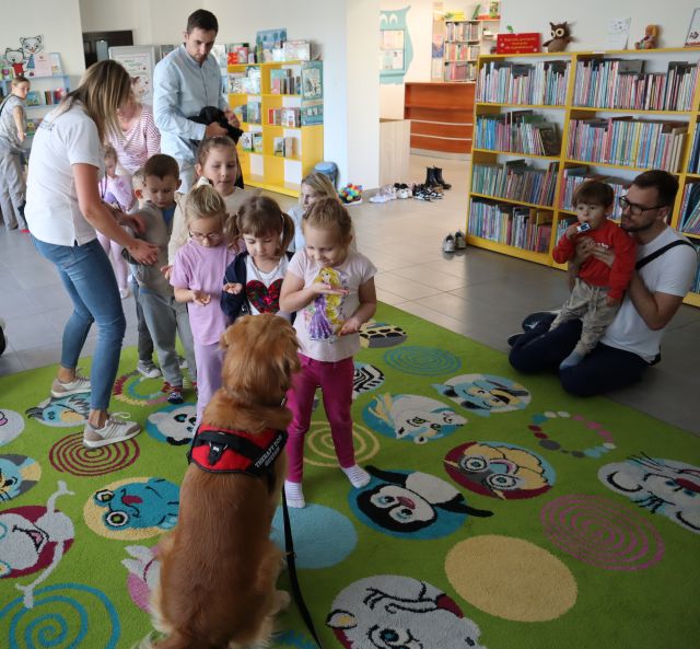 dzieci stoją w kolejce, aby dać psu smakołyki