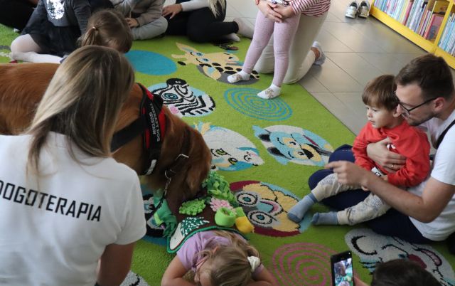 pies szuka na macie smakołyków, wokół mniego dzieci z rodzicami