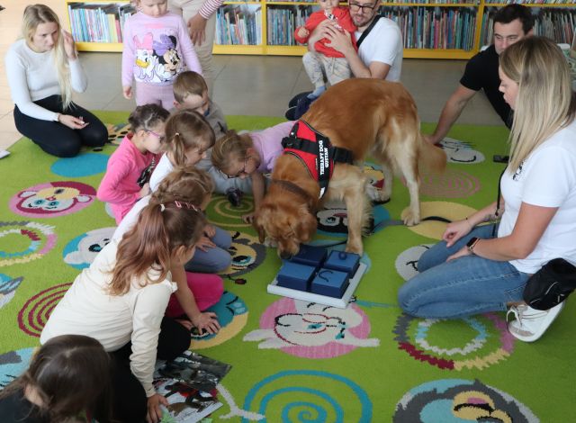 pies obwąchuje pudełęczka, dzieci wokół niego obserwują
