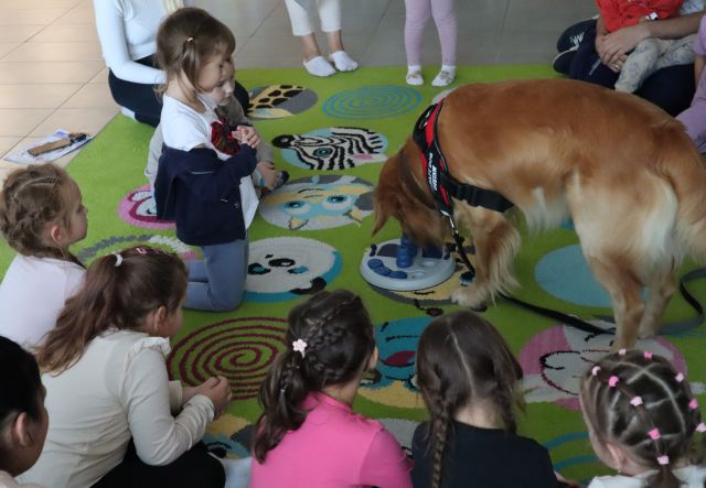 dzieci patrzą na psa obwąchującego zabawkę ze smakołykami