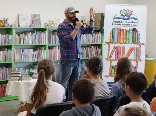 autor z mikrofonem stoi przed siedzącą młodzieżą