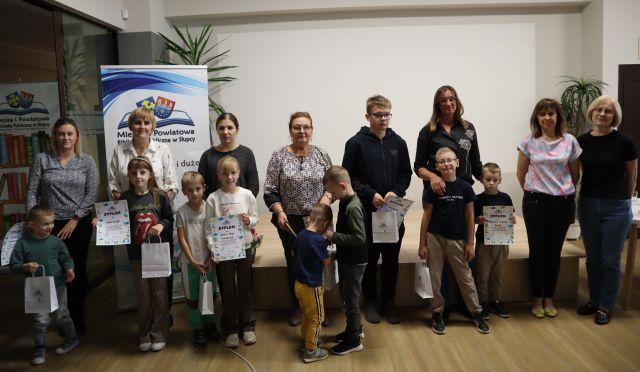 na zdjęciu dzieci z rodzicami nagrodzeni w konkursie z dyplomami i nagrodami