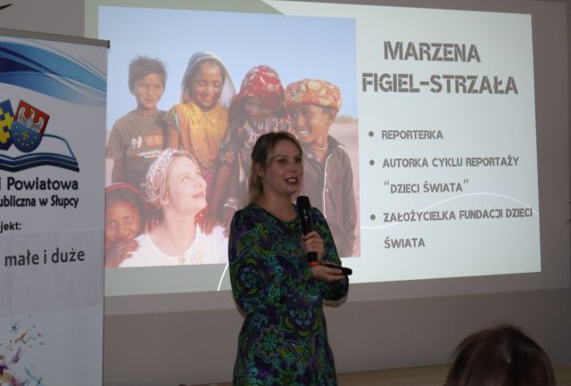 kobieta z mikrofonem, w tle jej wizytówka