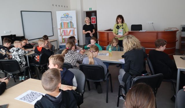 dyrektorka biblioteki pokazuje dzieciom książkę