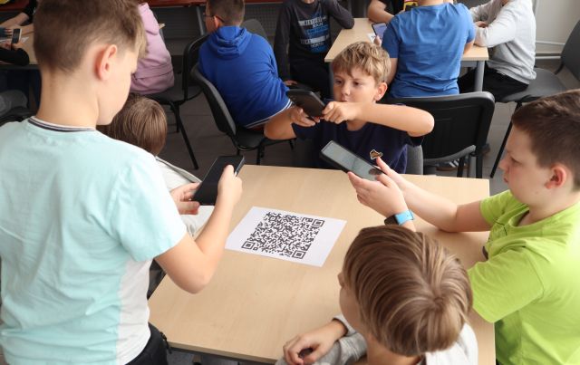 młodzież skanuje smartfonami kod kreskowy