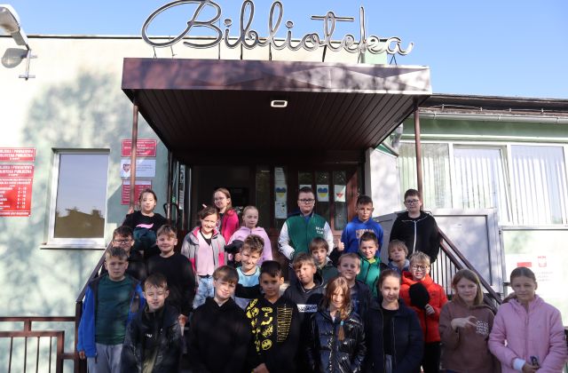 młodzież pozuje do zdjęcia na schodach przed wejściem do biblioteki