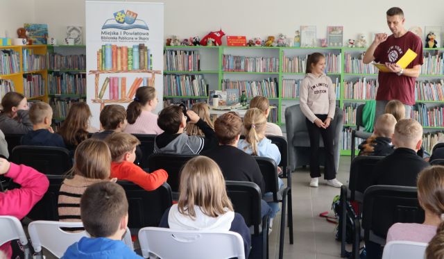 autor z dziewczynką stoją przed siedzącą na krzesłach młodzieżą