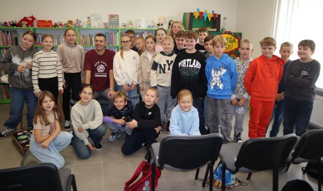 dzieci pozują do zdjęcia grupowego z autorem