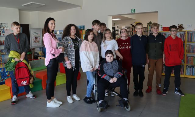 młodzież i nauczycielki pozują do zdjęcia, w tle regały biblioteczne