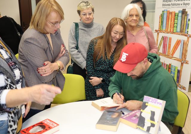 autor podpisuje książkę uczestniczkom spotkania
