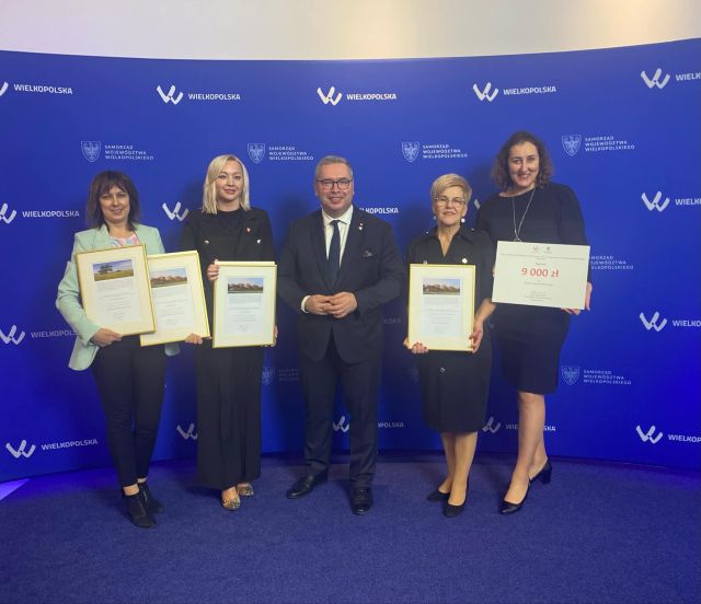 na zdjęciu 4 kobiety, w środku mężczyzna pozują do zdjęcia z dyplomami