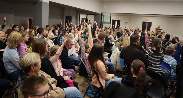 uczestnicy spotkania z podniesionymi rękami