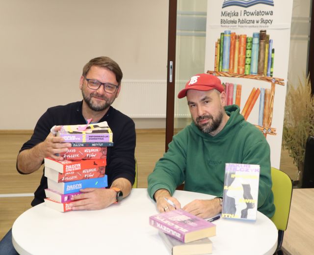 autor podpisuje książki uczestnikowi spotkania