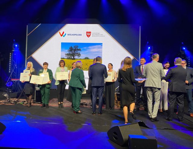 na zdjęciu osobyodbierające nagrody, w tle zdjęcie z logo konkursu