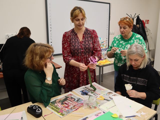 kobieta robi różę z materiału, obok kobiety przyglądają się