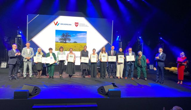 na zdjęciu osobyodbierające nagrody, w tle zdjęcie z logo konkursu