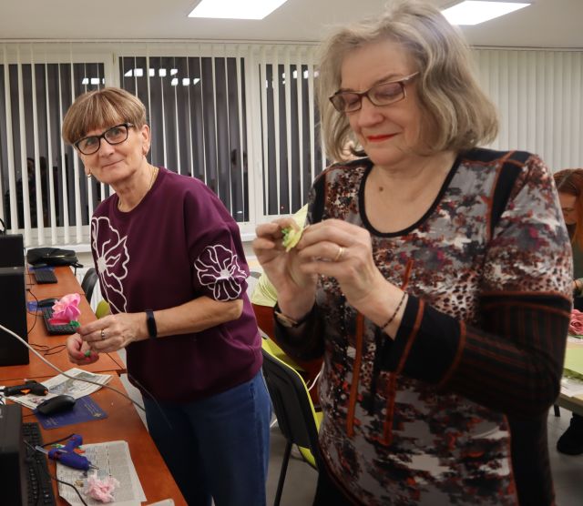 dwie kobiety robią kwiaty z materiałów