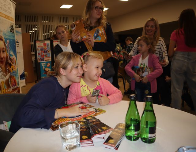 dziewczynka pozuje do zdjęcia z autorką, w tle inne dzieci