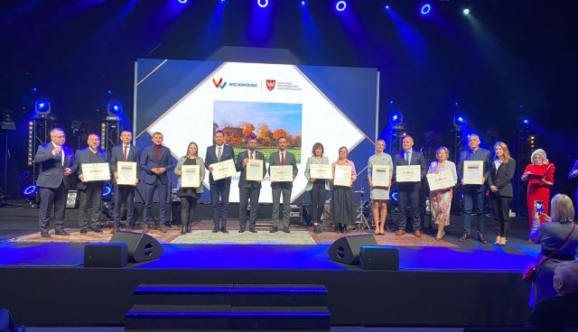 na zdjęciu osobyodbierające nagrody, w tle zdjęcie z logo konkursu