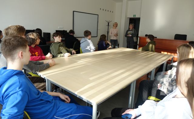 młodzież siedzi przy stołach w sali komputerowej