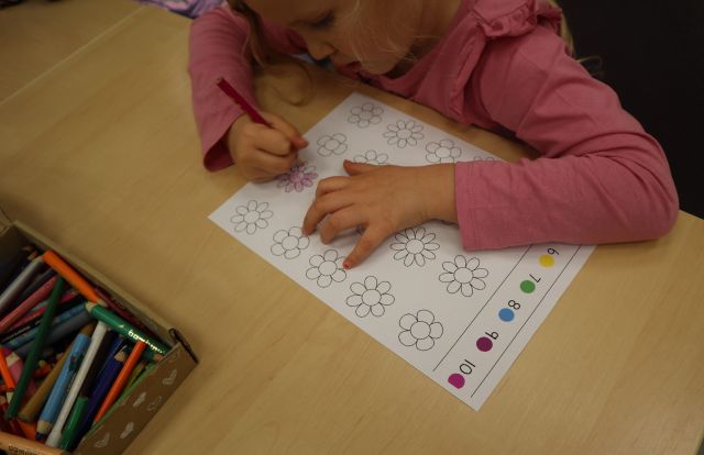 dziewczynka zakolorowuje rysunek z kwiatkami