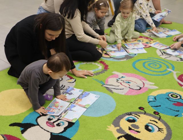 dzieci z rodzicami na kolorowym dywanie układają obrazki