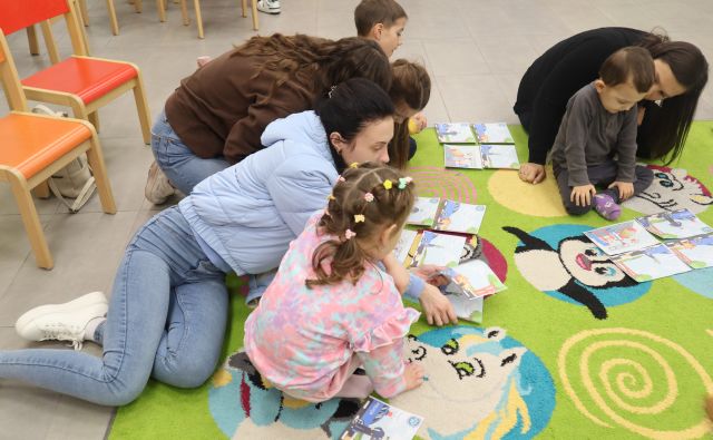 dzieci z rodzicami układają obrazki na kolorowym dywanie