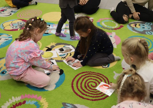 dzieci na kolorowym dywanie układają obrazki