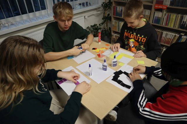 4 młodzieży przykleja kolorowe kwadraciki na kartki