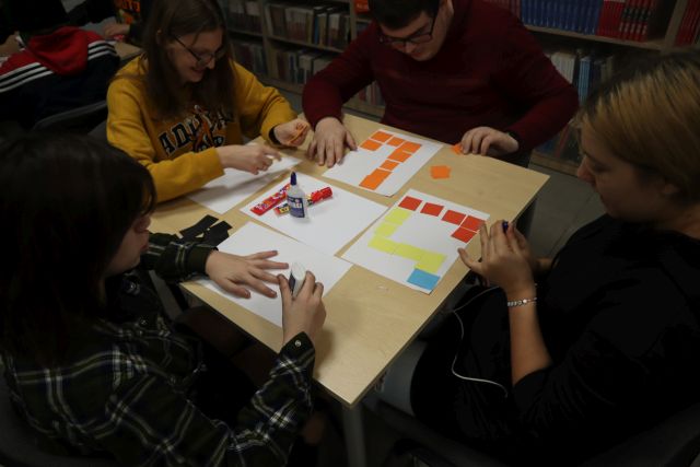 4 młodzieży przykleja kolorowe kwadraciki na kartki