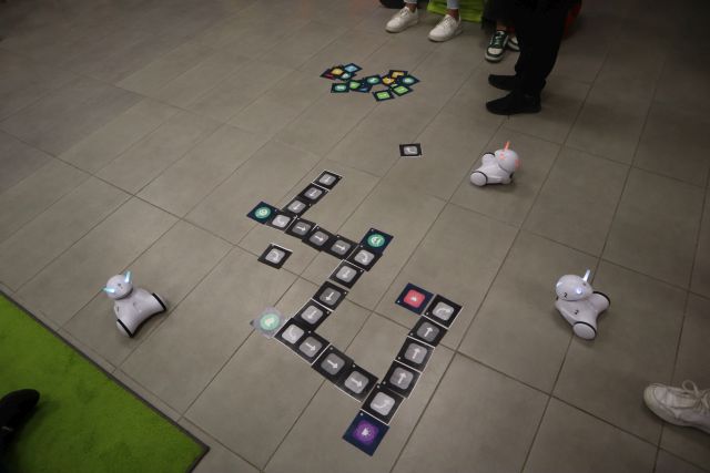 na podłodze kolorowe obrazki, a obok roboty Photon