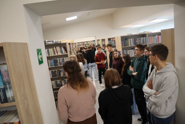 młodzież spaceruje po pomieszczeniu z księgozbiorem dla czytelników dorosłych