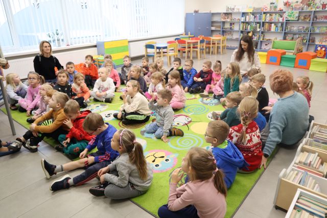 przedszkolaki siedzą na kolorowym dywanie