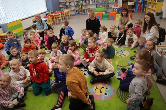 przedszkolaki siedzą na kolorowym dywanie