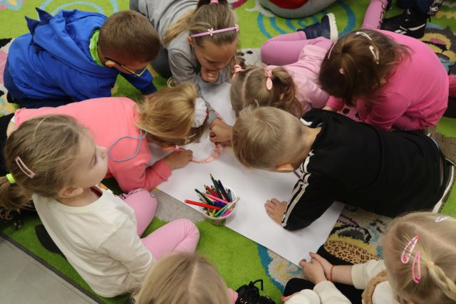 przedszkoalki kolorują postać z bajki na dużym arkuszu papieru