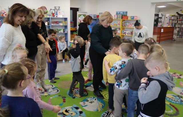 przedszkolaki stoją z nauczycielkami przy buźkach z papieru