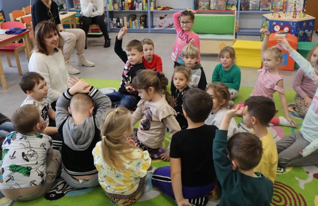 przedskolaki siedzą na dywanie i podnoszą palce
