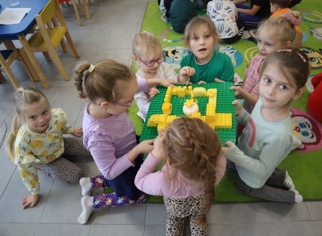 dziewczynki trzymają w rękach tabliczkę z klockami LEGO