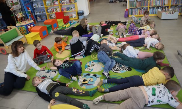 przedszkolaki leżą na kolorowym dywanie