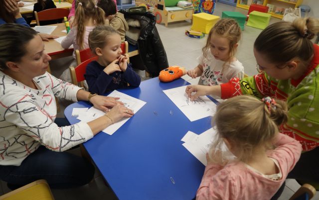 małe dzieci z rodzicami malują na kartkach