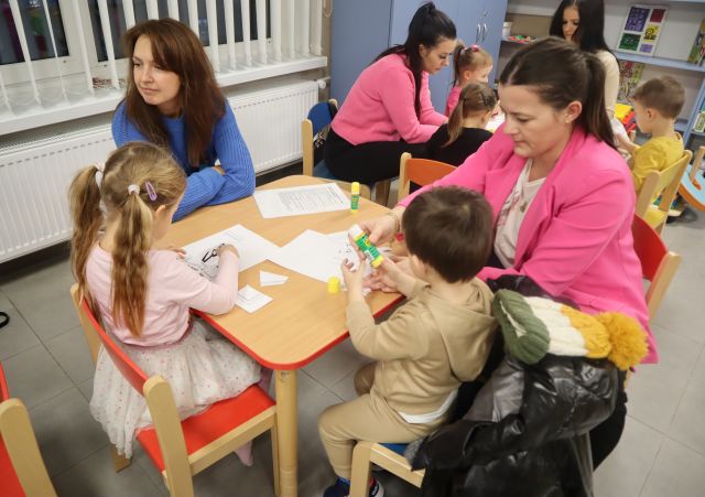 małe dzieci z rodzicami malują na kartkach