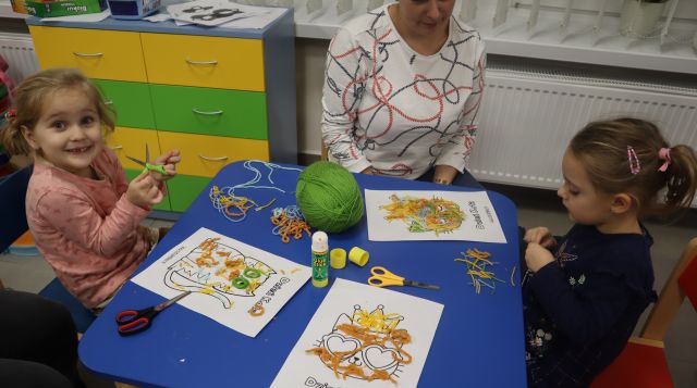 dzieci z rodzicami wyklajają koty wełną