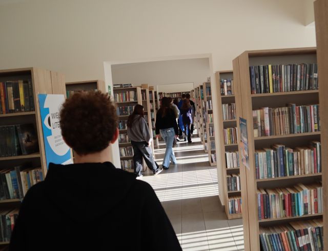 młodzież spaceruje między regałami z książkami