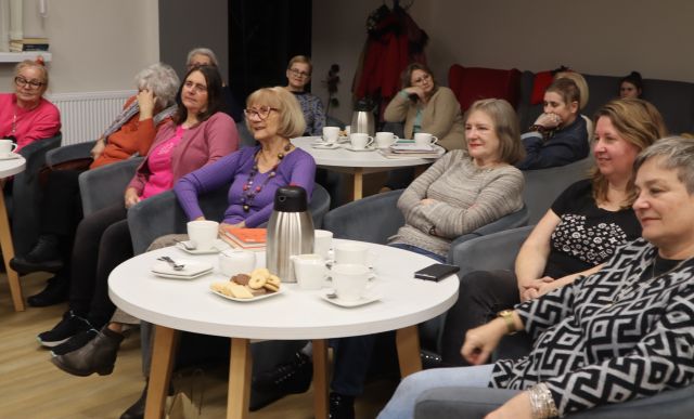 uczestniczki spotkania siedzą na fotelach przy okrągłych stołach