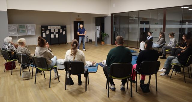 uczestnicy szkolenia siedzą na krzesłach, przed nimi stoi prowadzący