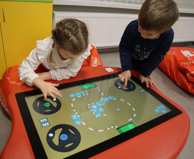 chłopiec i dziewczynka grają na stoliku interaktywnym
